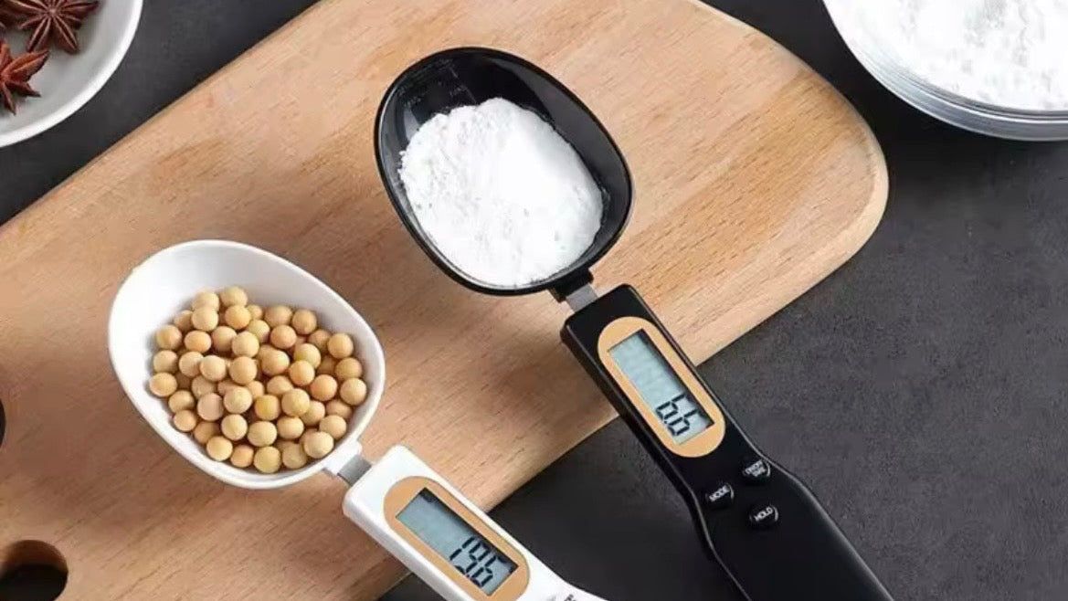 Digital measuring spoon with digital display on a wooden cutting board with ingredients.